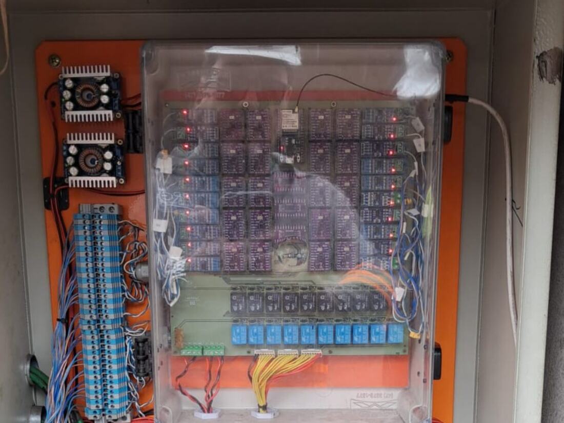 Quadro de comando aberto, com relés, borneiras identificadas e controlador de carga solar