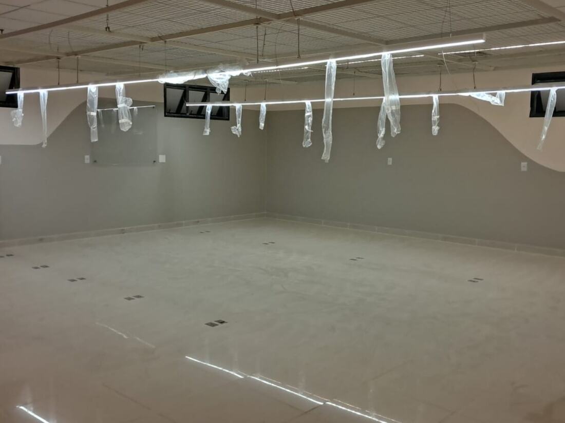 Sala comercial concluída, com forro modular, luminárias lineares e piso polido